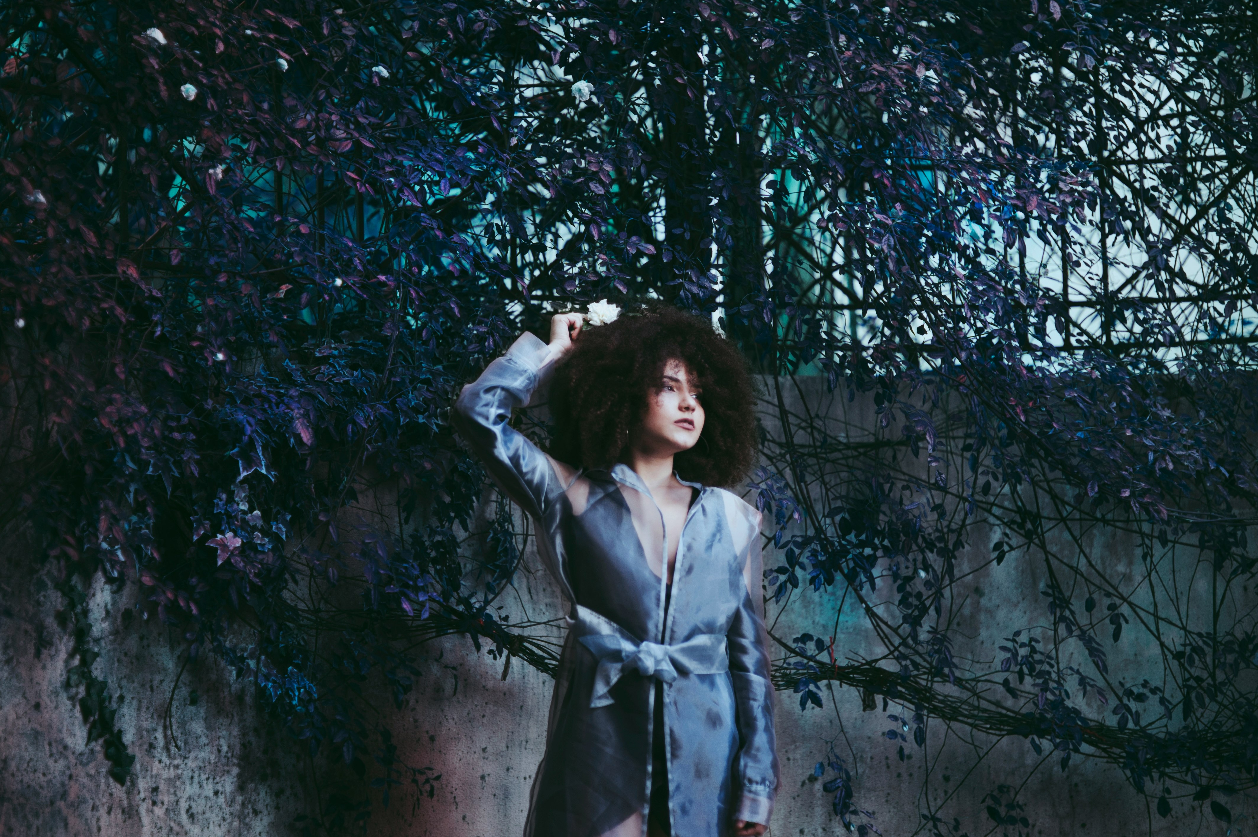 woman posing near wall with tree